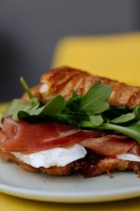 Zbliżenie wytrawnego croissanta z rukolą w kawiarni WyBawialnia